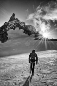 il dente del gigante , l'alba ed il sorgere del sole dietro alla cresta de Rochefort. La guida alpina vista di spalle, progredisce sul ghiacciaio verso il dente del Gigante.
